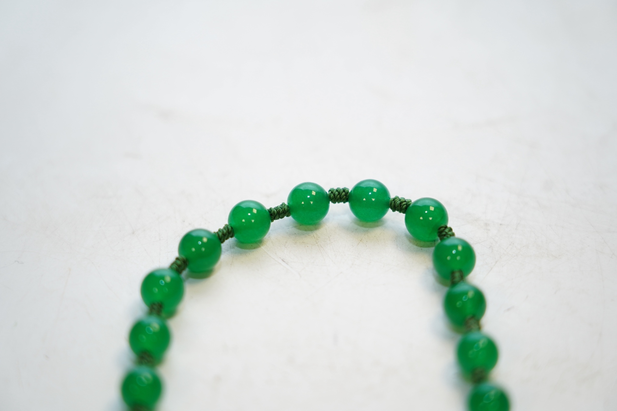 A single strand jadeite bead necklace, with simulated gemstone set clasp, 56cm. Condition - fair